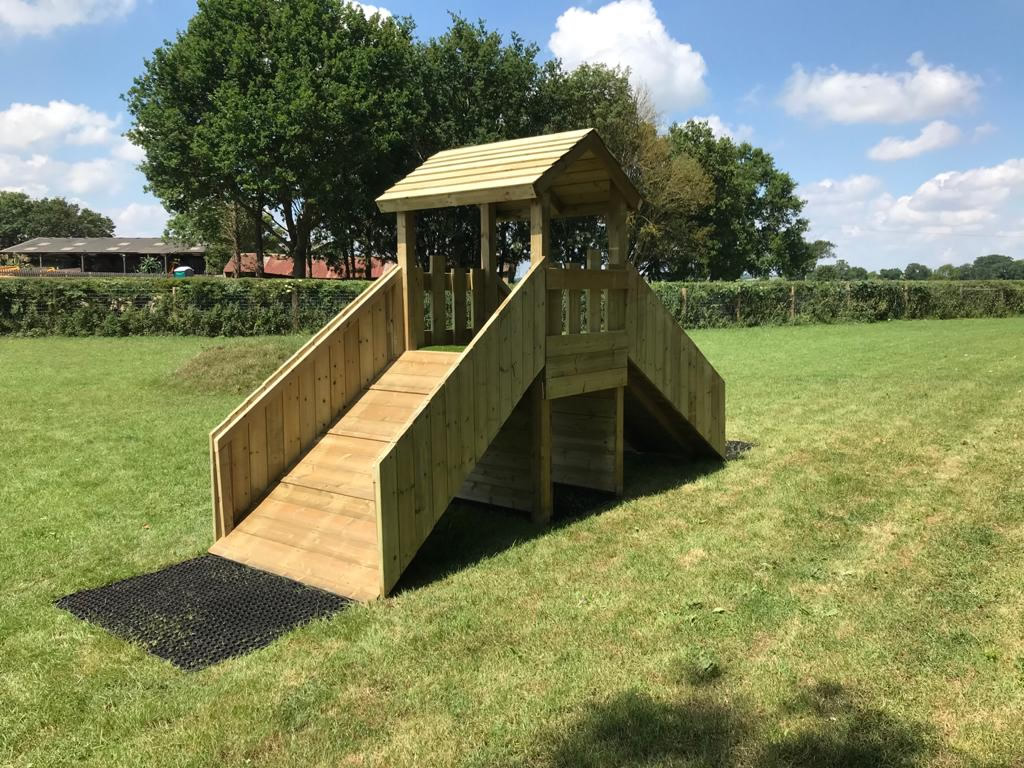 A wooden play tower with ramps and tiled roof