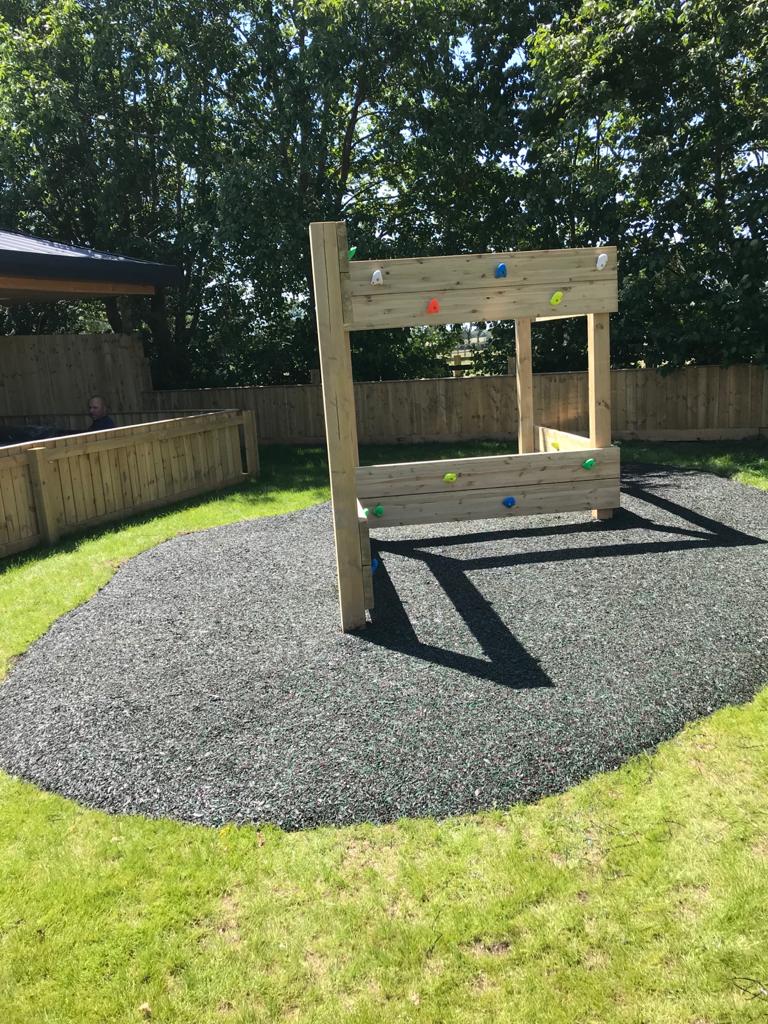 Outdoor play climbing wall with safety surfacing below