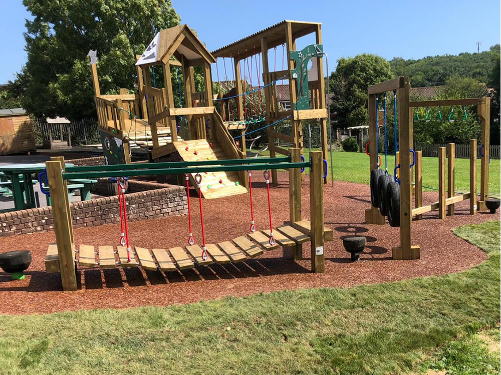 A swing bridge and climbing ramp at a play area